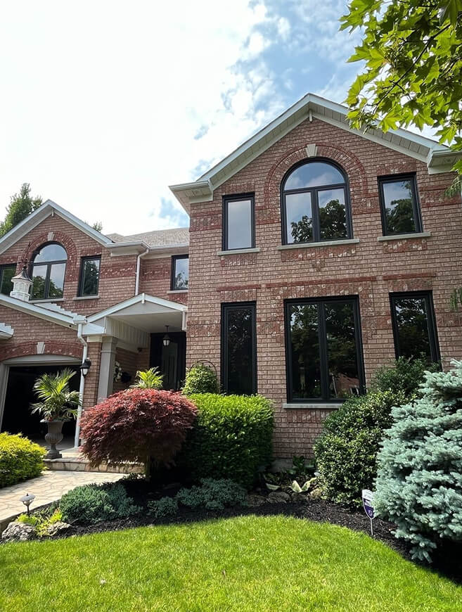 Custom arched transom and matching dark-frame windows on a brick home.