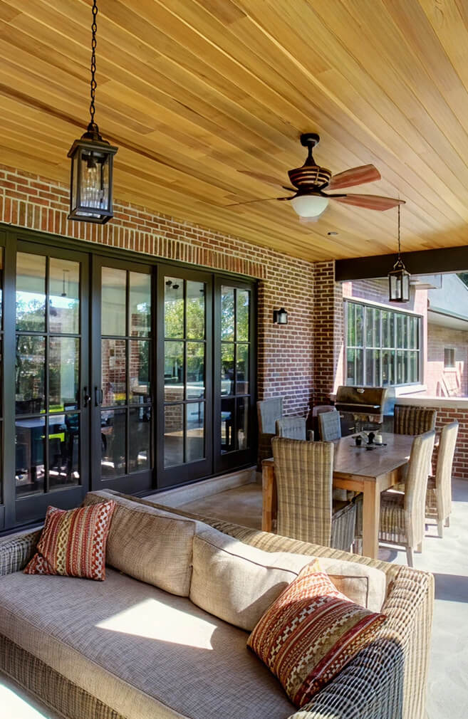 Custom black-frame folding patio doors and a large architectural window on a covered patio.