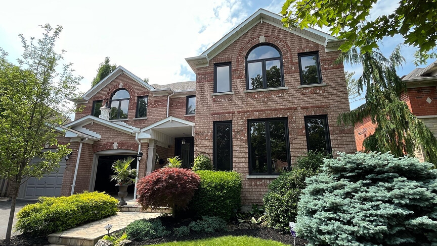 Custom multi-pane architectural windows and a dark front entry door on a luxury home exterior.
