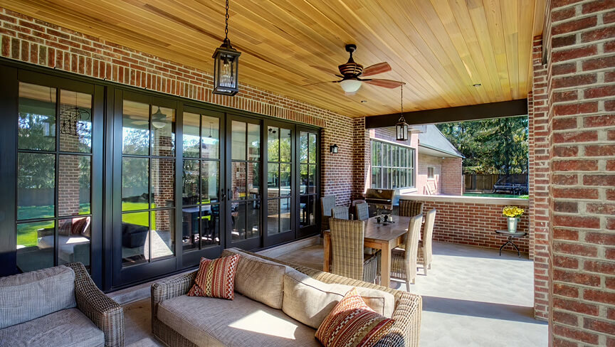 Custom black-frame folding patio doors and a large architectural window opening onto a covered patio.