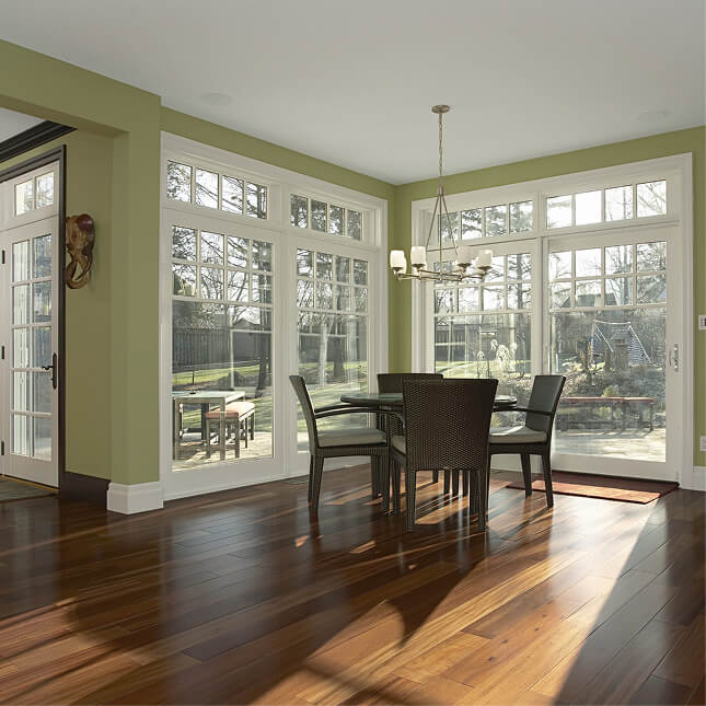 Bright dining room with white-trimmed patio doors and tall transom windows overlooking the backyard.