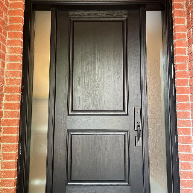 Black custom entry door with raised panels, narrow frosted sidelights and a contemporary handle set.
