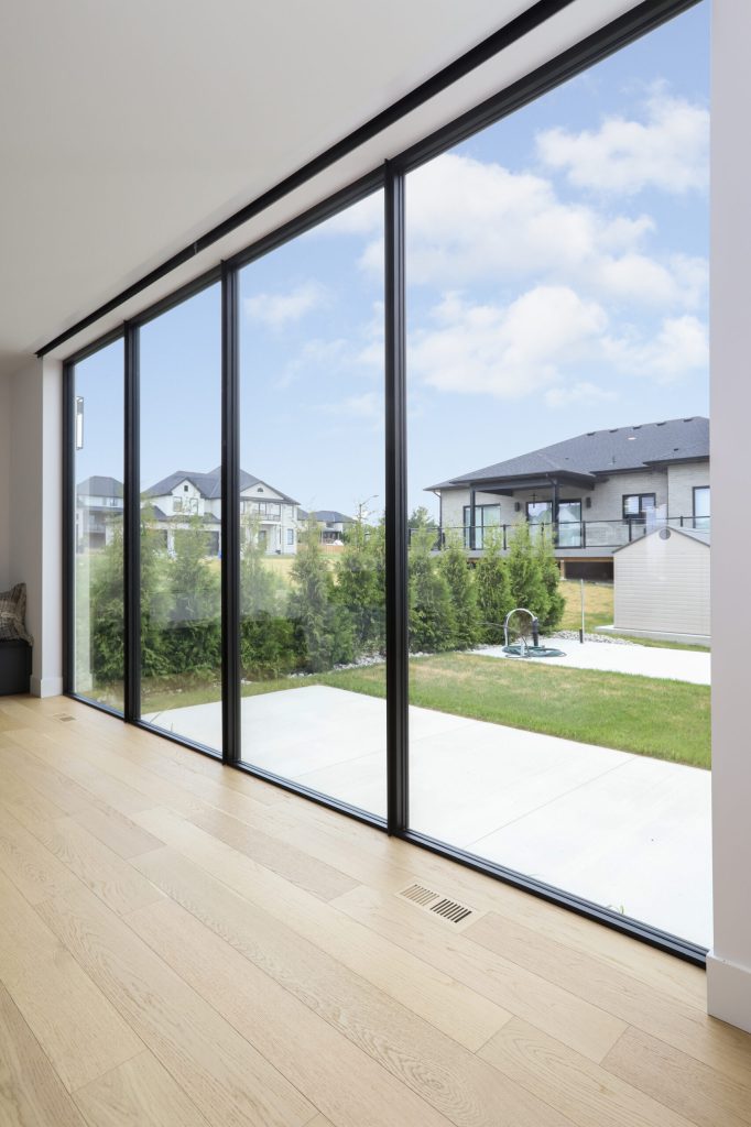 Black-framed lift-and-slide glass doors opening onto a lawn